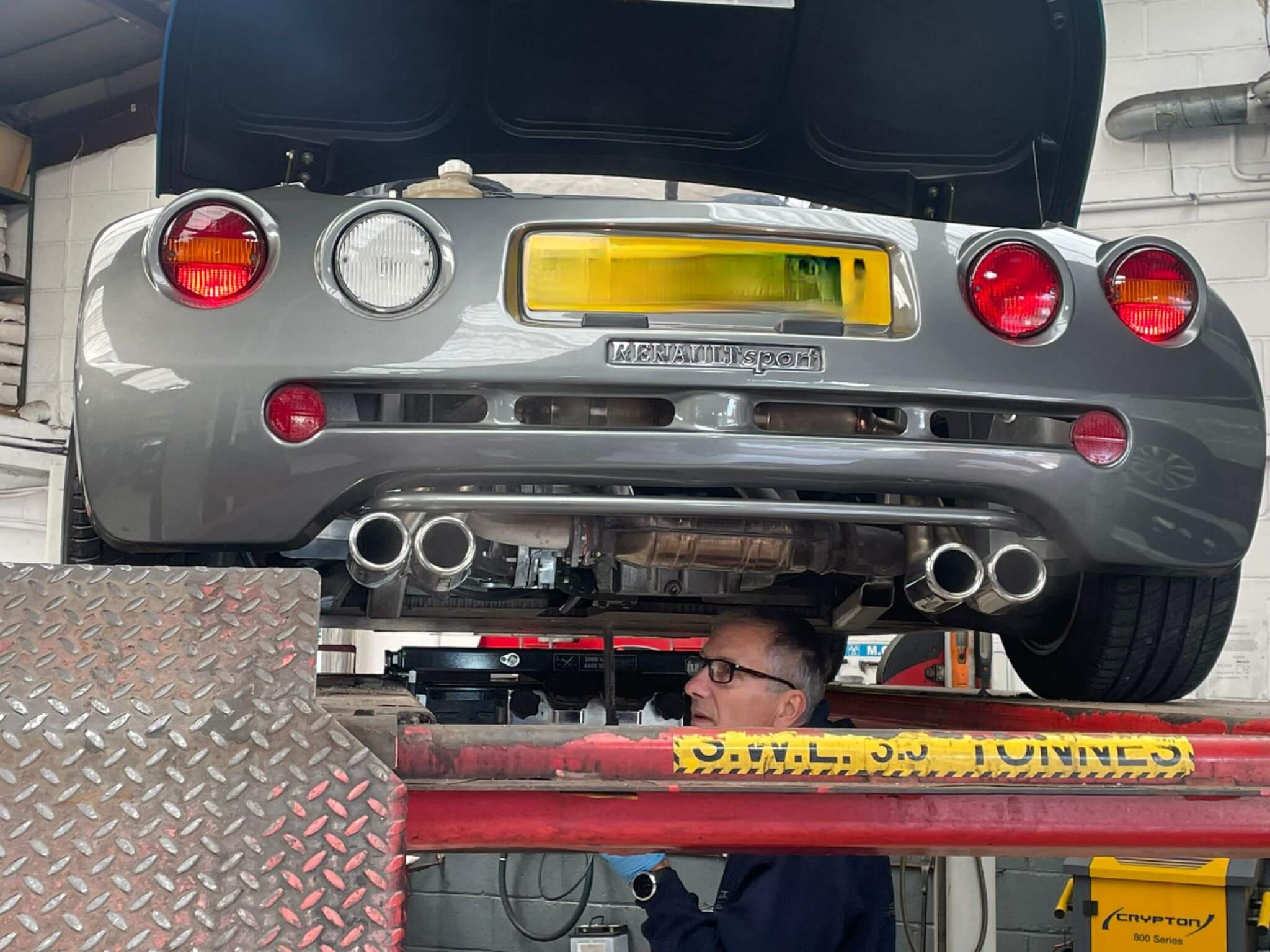 silver renault sport with mechanic underneath
